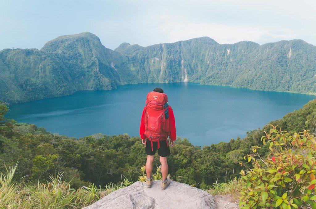 Photo by Robert Forever Ago Hiker with backpack enjoying scenic mountain lake view on a bright summer day.